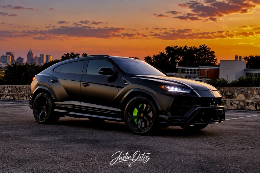 Matte black Lamborghini Urus at sunset with the San Antonio skyline behind it